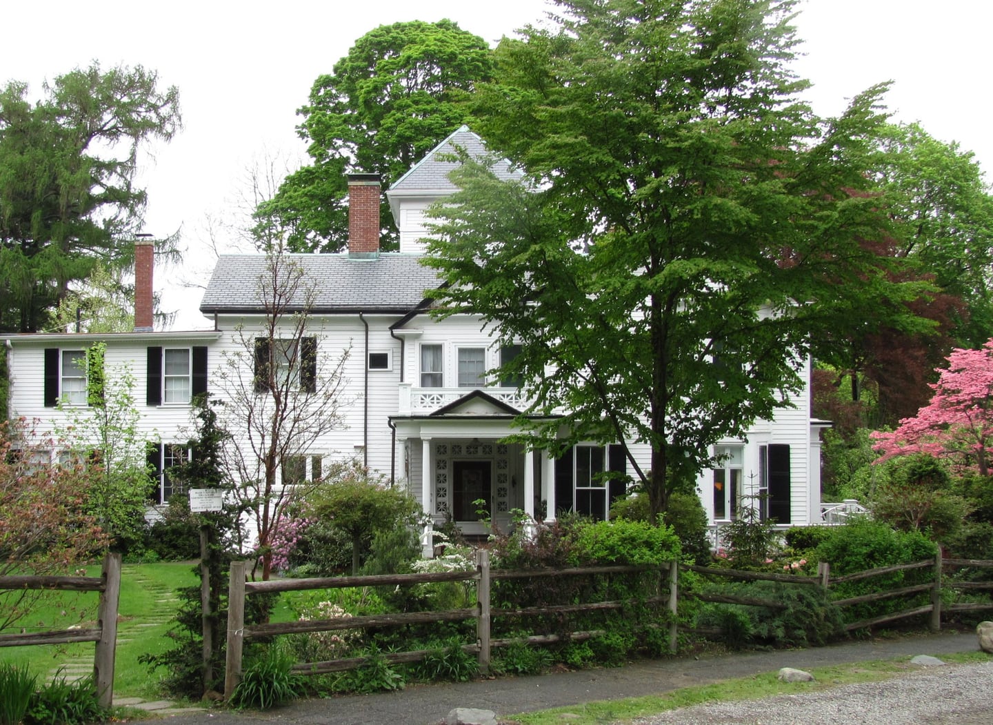 White historic home surrounded by leafy gardens in Newton Centre, Massachusetts